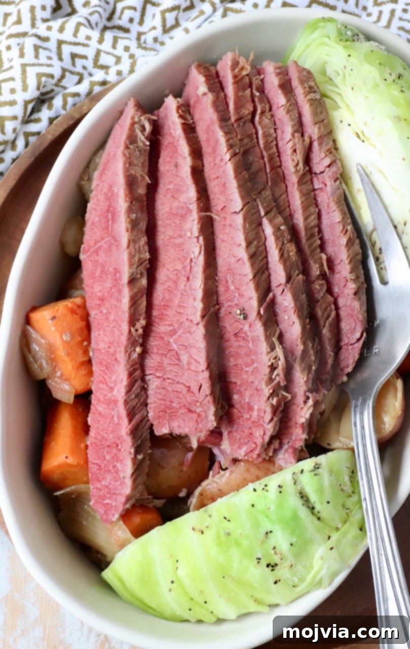 Generous slices of savory corned beef served alongside a pile of vibrant, perfectly steamed cabbage in a rustic serving dish, creating a classic and comforting meal.