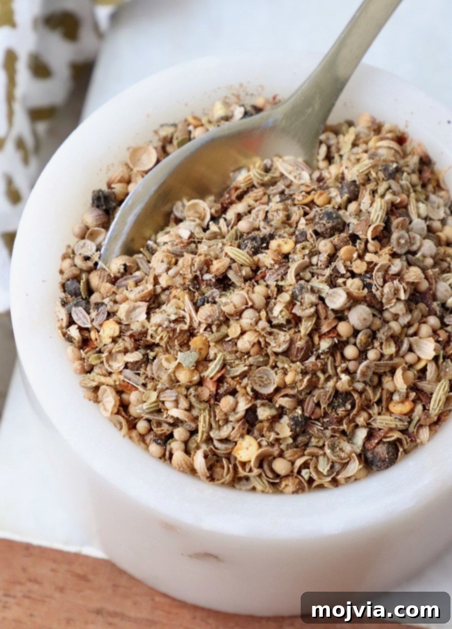 Signature Corned Beef Spice Blend 2 A small bowl filled with homemade corned beef seasoning, accompanied by a miniature spoon, highlighting its coarse texture and vibrant spice blend.