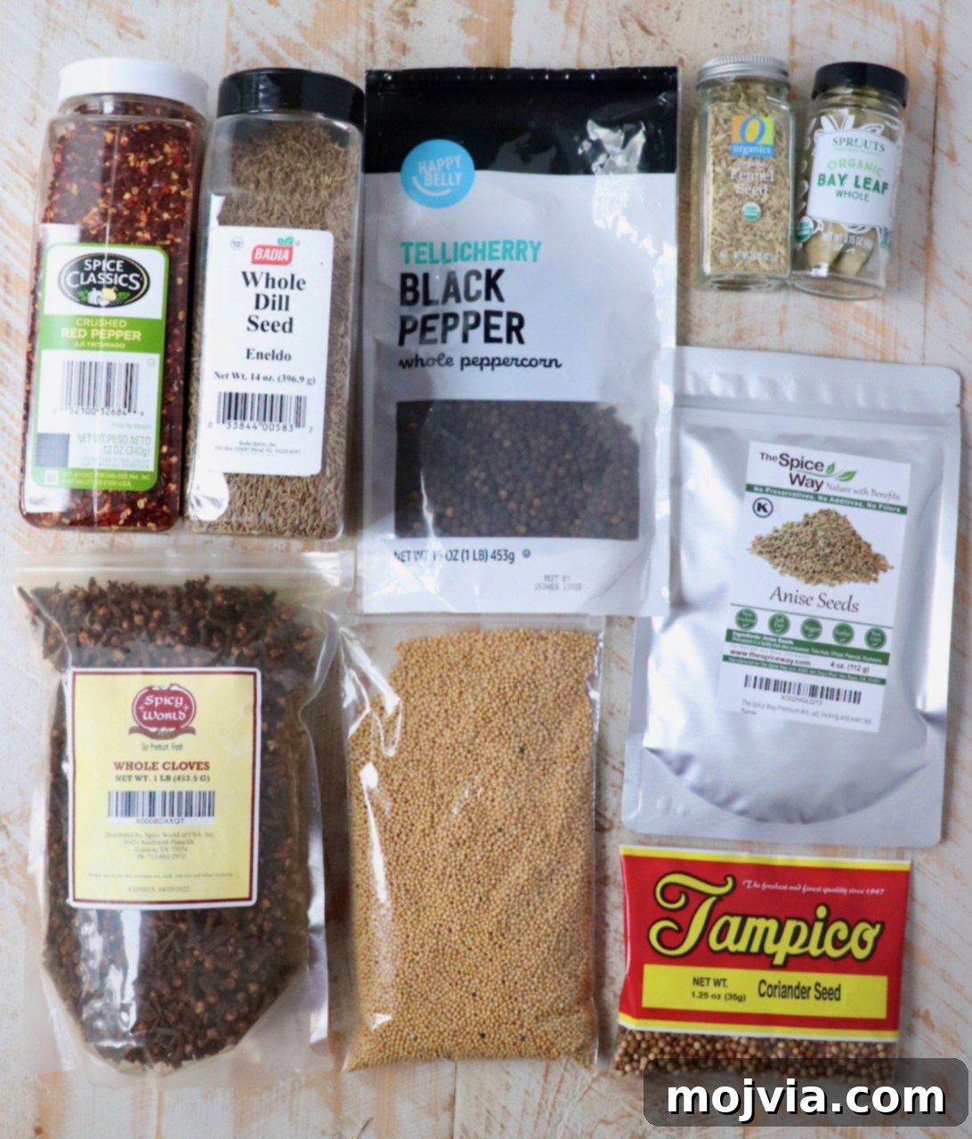 Signature Corned Beef Spice Blend 3 An array of whole spices laid out on a white wooden board, including coriander seeds, mustard seeds, peppercorns, anise seeds, fennel seeds, dill seeds, whole cloves, bay leaves, and crushed red pepper flakes, ready for making homemade corned beef seasoning.