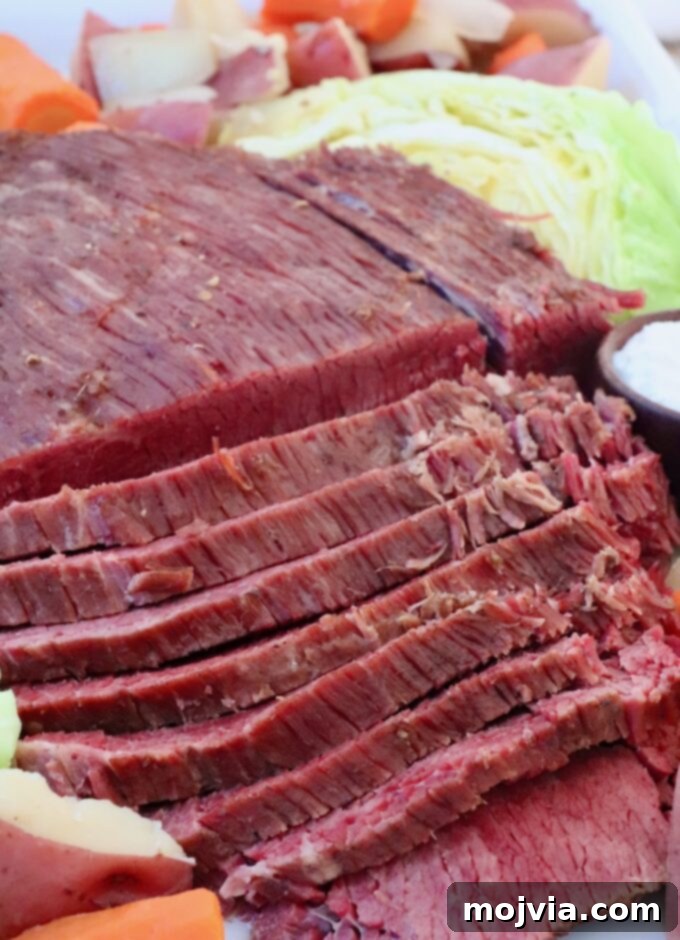 Signature Corned Beef Spice Blend 7 Beautifully sliced corned beef brisket served on a large platter, surrounded by tender cooked carrots, potatoes, and steamed cabbage, all infused with rich seasoning.