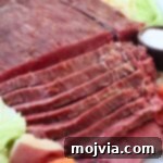 sliced corned beef on plate with cabbage, potatoes and carrots