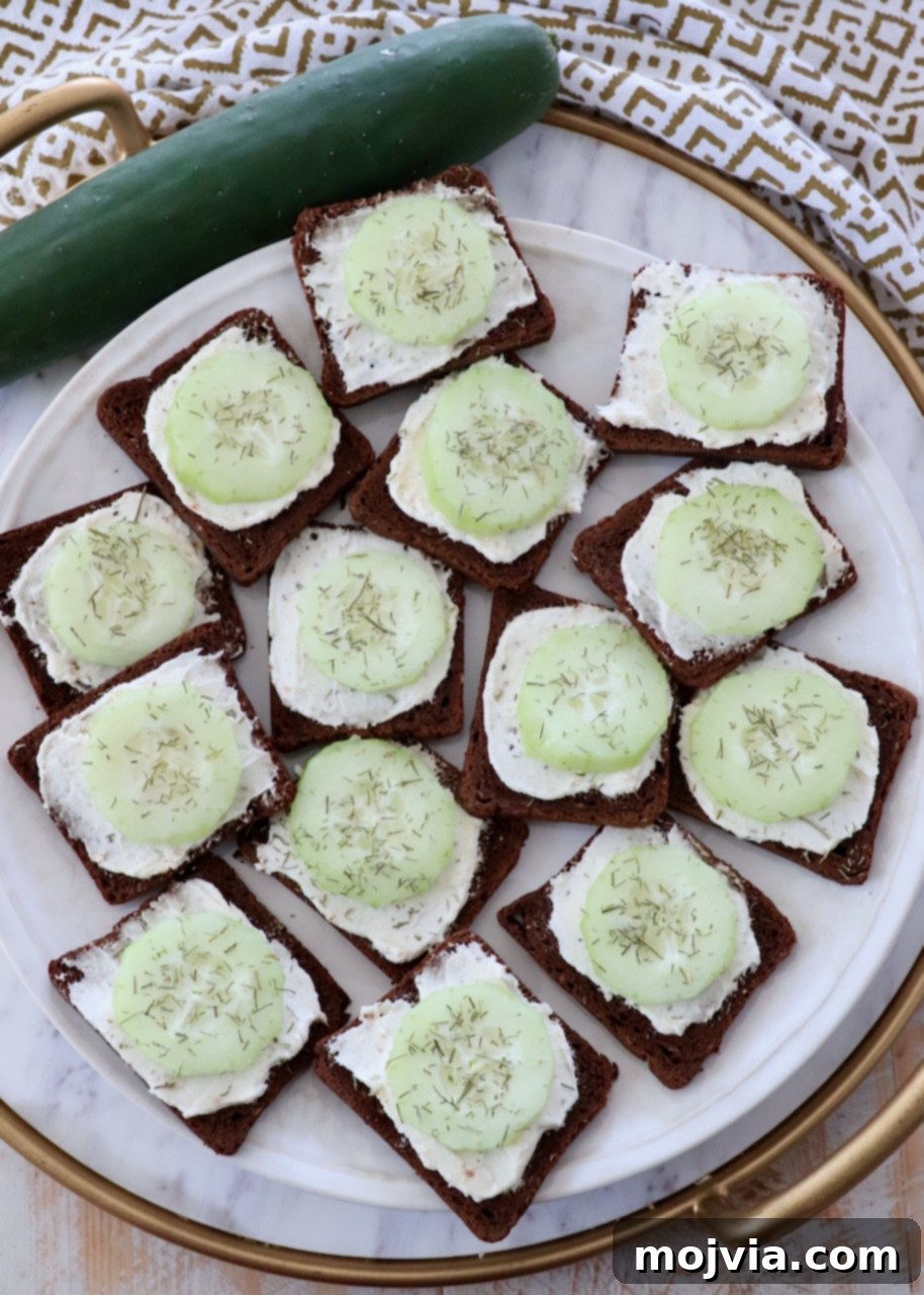 Delicate Cucumber Delights 2 Open-face cucumber tea sandwiches beautifully arranged on a marble serving tray