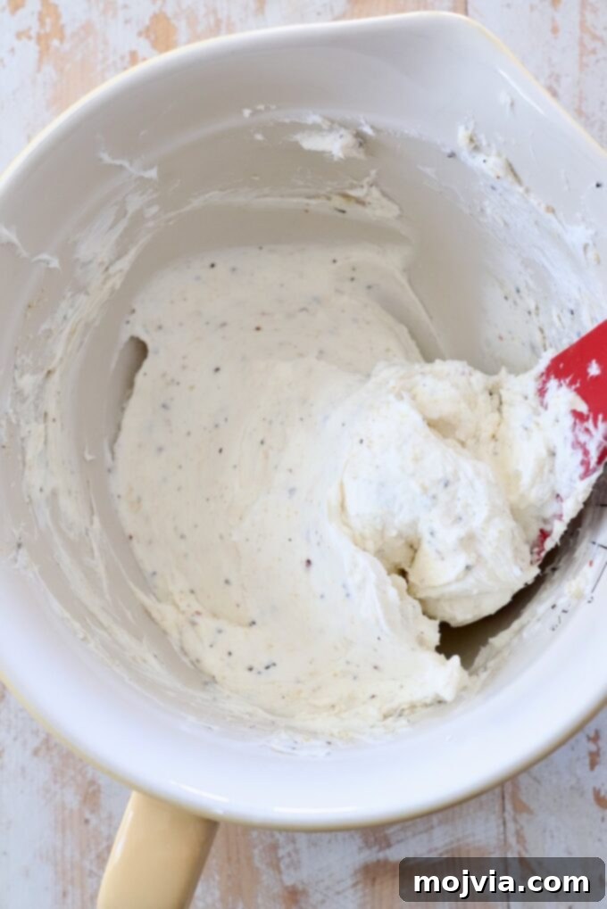 Delicate Cucumber Delights 4 Seasoned cream cheese in a bowl with a spatula, ready to be spread.