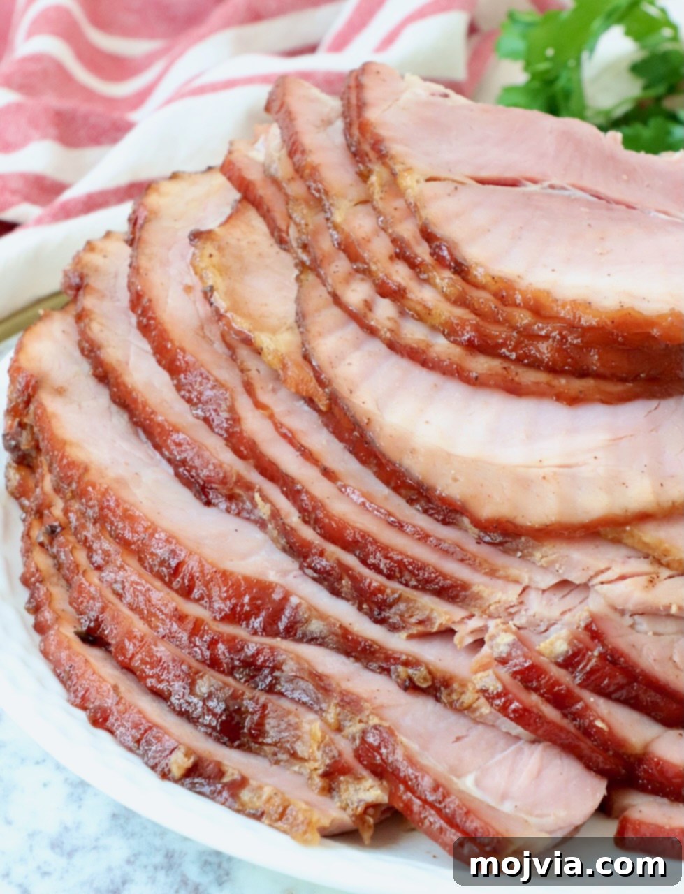 Golden Honey Glazed Ham Feast 12 Stacked slices of honey baked ham on a serving plate.