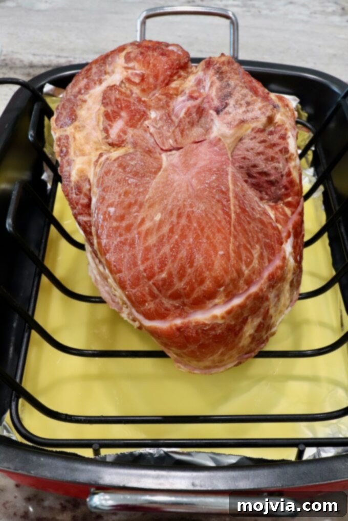Golden Honey Glazed Ham Feast 4 Spiral ham placed in a roasting pan with pineapple juice at the bottom.