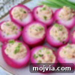 Beet pickled deviled eggs beautifully arranged on a serving platter.