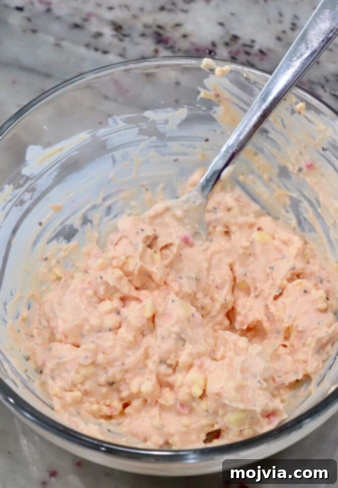 Creamy beet pickled deviled egg filling in a glass bowl with a spoon, showing its smooth texture.
