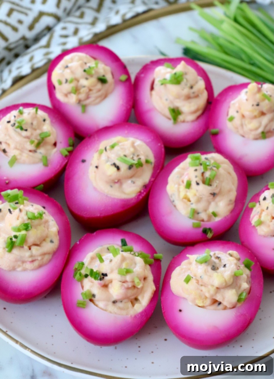 A serving platter of stunning beet deviled eggs, showcasing their bright pink color and creamy filling.