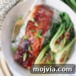 filet of cooked miso glazed salmon in bowl with fork and baby bok choy