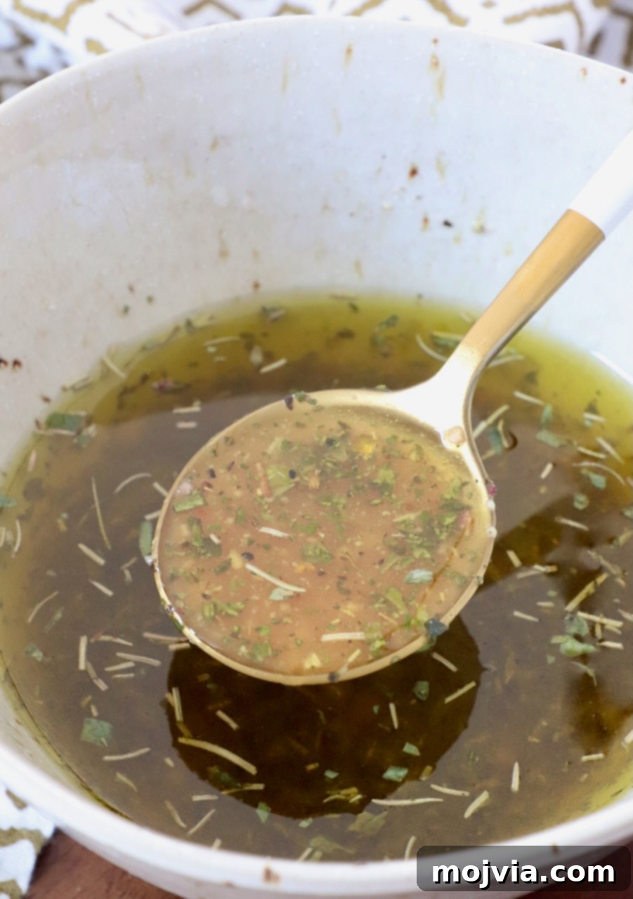 Freshly made Italian salad dressing in a glass bowl with a spoon, ready to be served over a vibrant green salad.