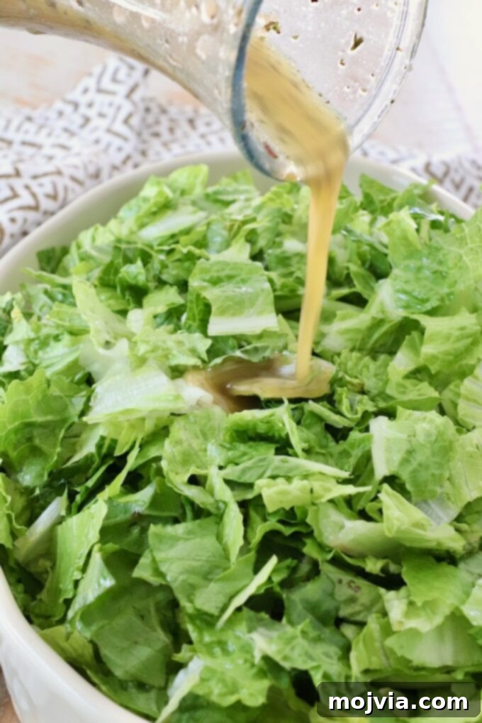 Freshly made Italian dressing being poured over a bowl of crisp chopped greens, illustrating its use in a salad.