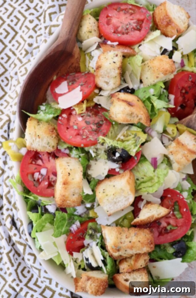 A large serving bowl filled with a colorful Italian salad, ready to be tossed with dressing and served.