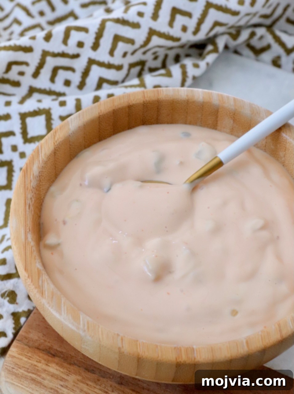 Secret Burger Sauce 2 A bowl of creamy, orange-tinted burger sauce with a small spoon, ready to be served
