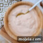 A bowl of creamy homemade burger sauce with a small spoon, ready for serving