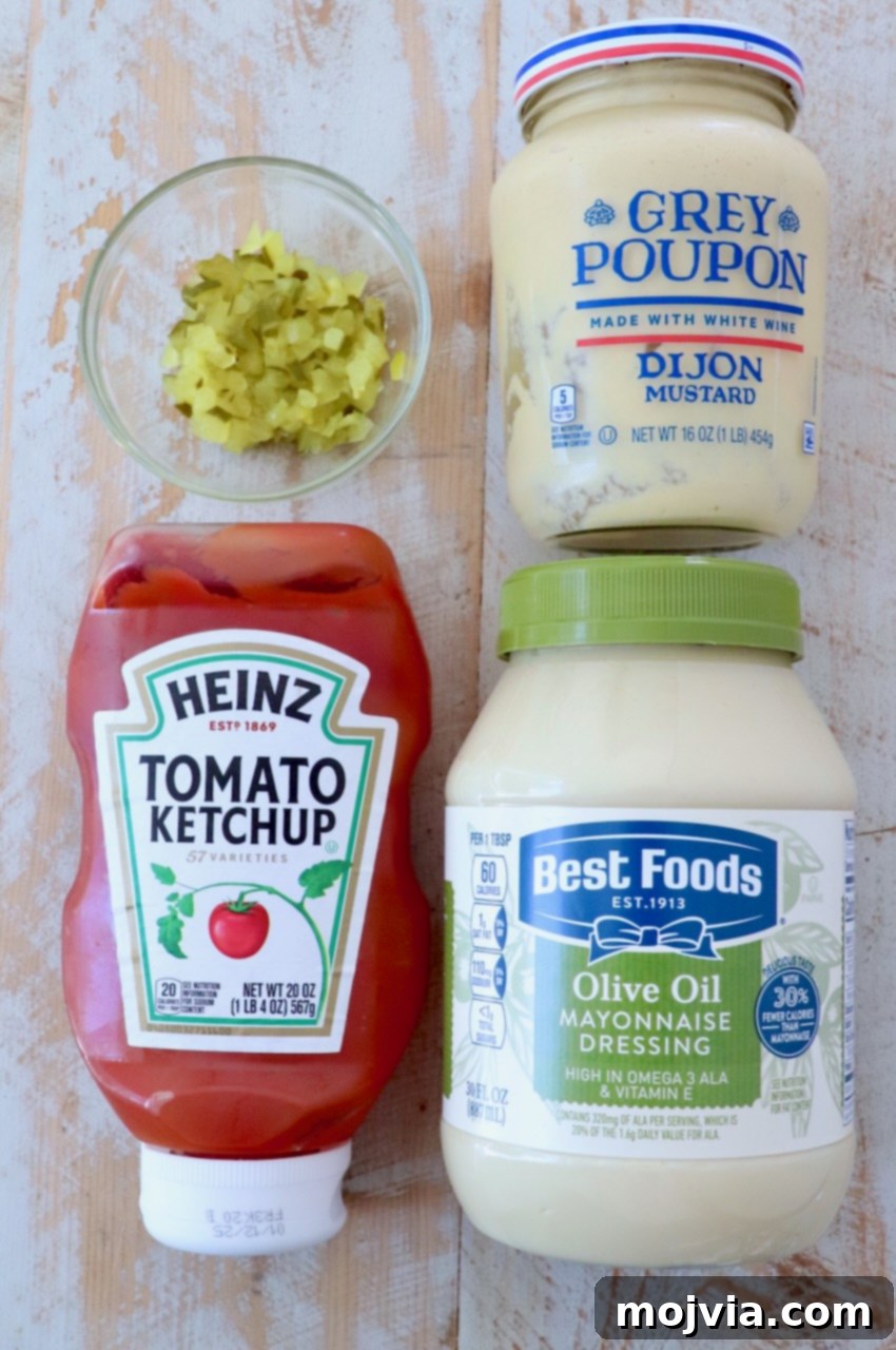 Secret Burger Sauce 3 Individual ingredients for burger sauce (mayonnaise, ketchup, finely diced pickles, dijon mustard) arranged neatly on a white wooden board