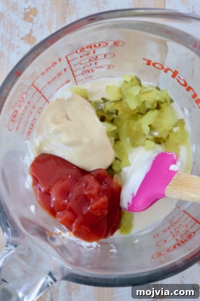 Secret Burger Sauce 4 Separate bowls of ketchup, dijon mustard, mayonnaise, and finely diced pickles, showcasing the fresh ingredients before mixing