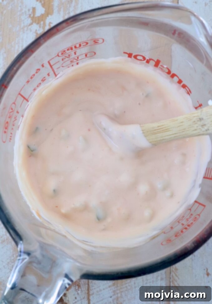 Secret Burger Sauce 5 A glass jar filled with freshly mixed homemade burger sauce, showing its creamy texture and small pickle pieces
