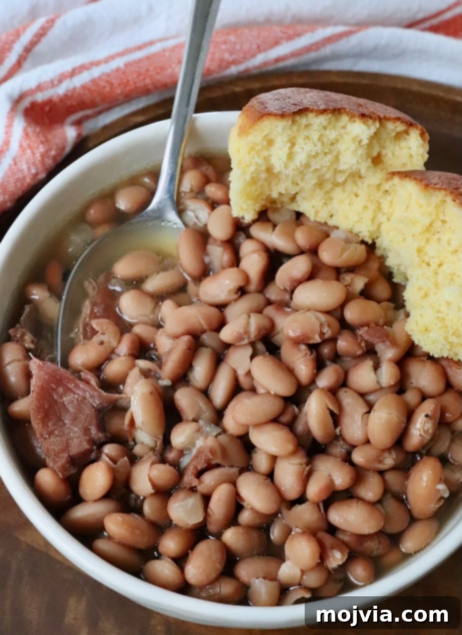 The Humble Pinto: A Culinary Staple 2 pinto beans in bowl with spoon and cornbread muffin on the side