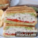Herbed Turkey Pesto Stack 10 A delicious turkey pesto sandwich, sliced in half and stacked on a plate, ready to be enjoyed.