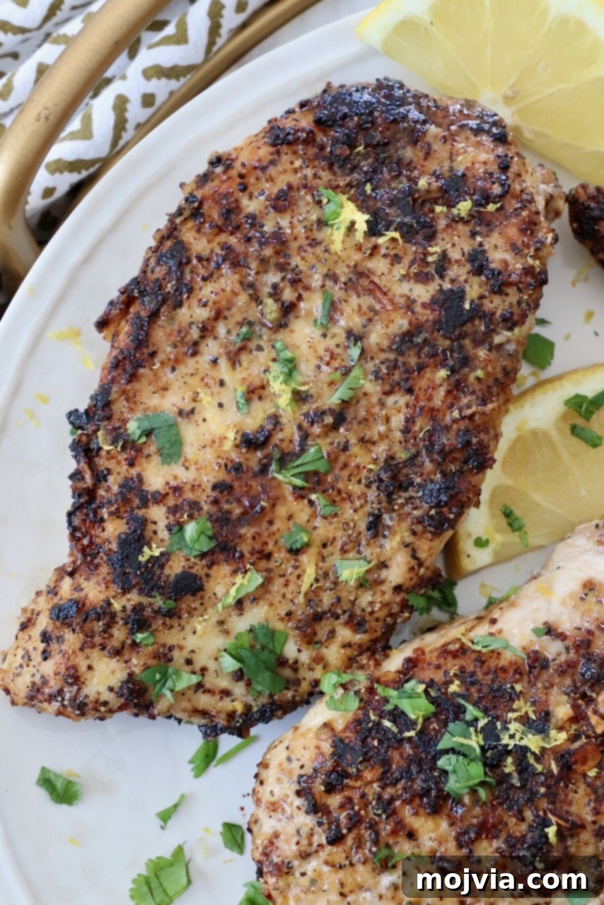 Zesty Lemon Pepper Blend 5 Perfectly cooked lemon pepper chicken breasts elegantly arranged on a plate, garnished with vibrant lemon slices, ready to be enjoyed.