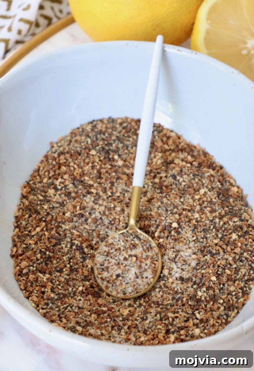 Zesty Lemon Pepper Blend 6 A charming bowl filled with vibrant homemade lemon pepper seasoning, accompanied by a small spoon, highlighting its texture and fresh appeal.