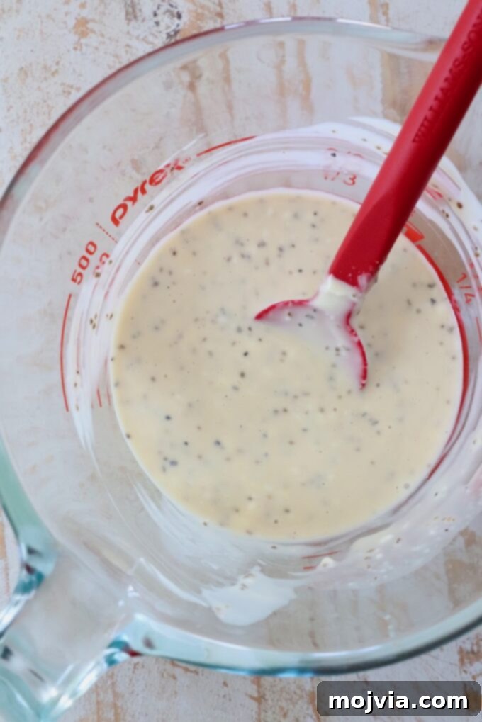Zesty Coleslaw Dressing 5 Coleslaw dressing being stirred in a glass measuring cup with a red spatula