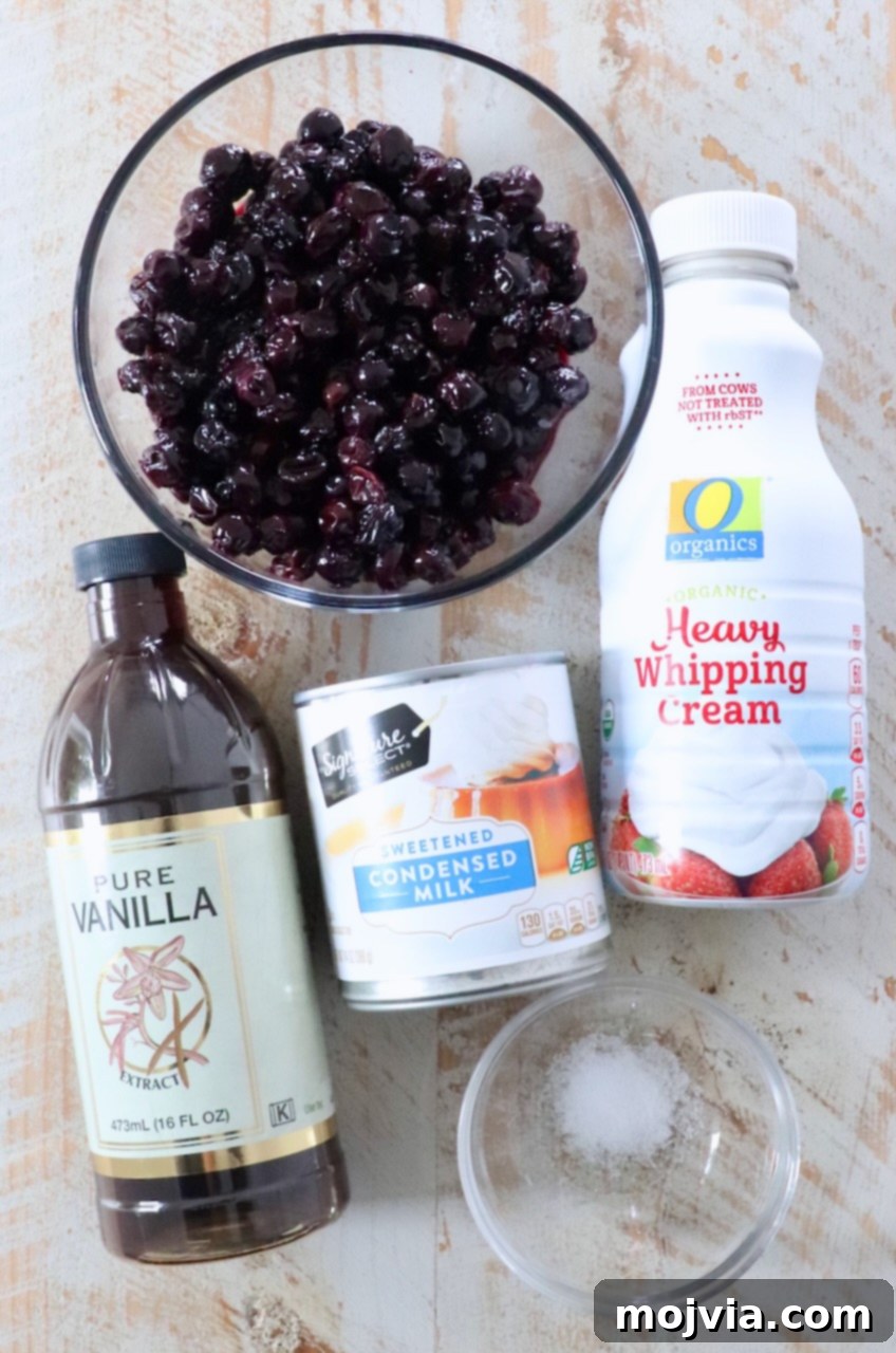 Frosted Blueberry Dream 3 A selection of fresh ingredients laid out on a white wooden board, including blueberries, a can of sweetened condensed milk, and heavy cream, ready for making homemade blueberry ice cream.