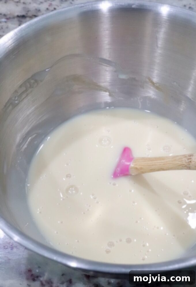 Frosted Blueberry Dream 6 Sweetened condensed milk, vanilla extract, and salt being mixed together in a bowl with a small spatula, forming the base for the no-churn ice cream.