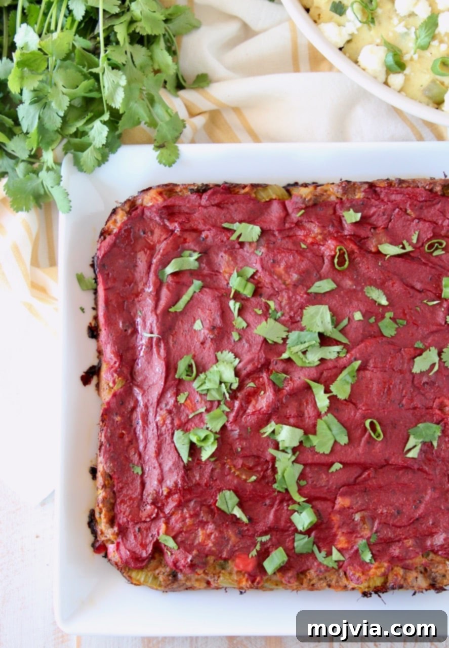Cooked Mexican meatloaf on white plate topped with tomato paste and cilantro