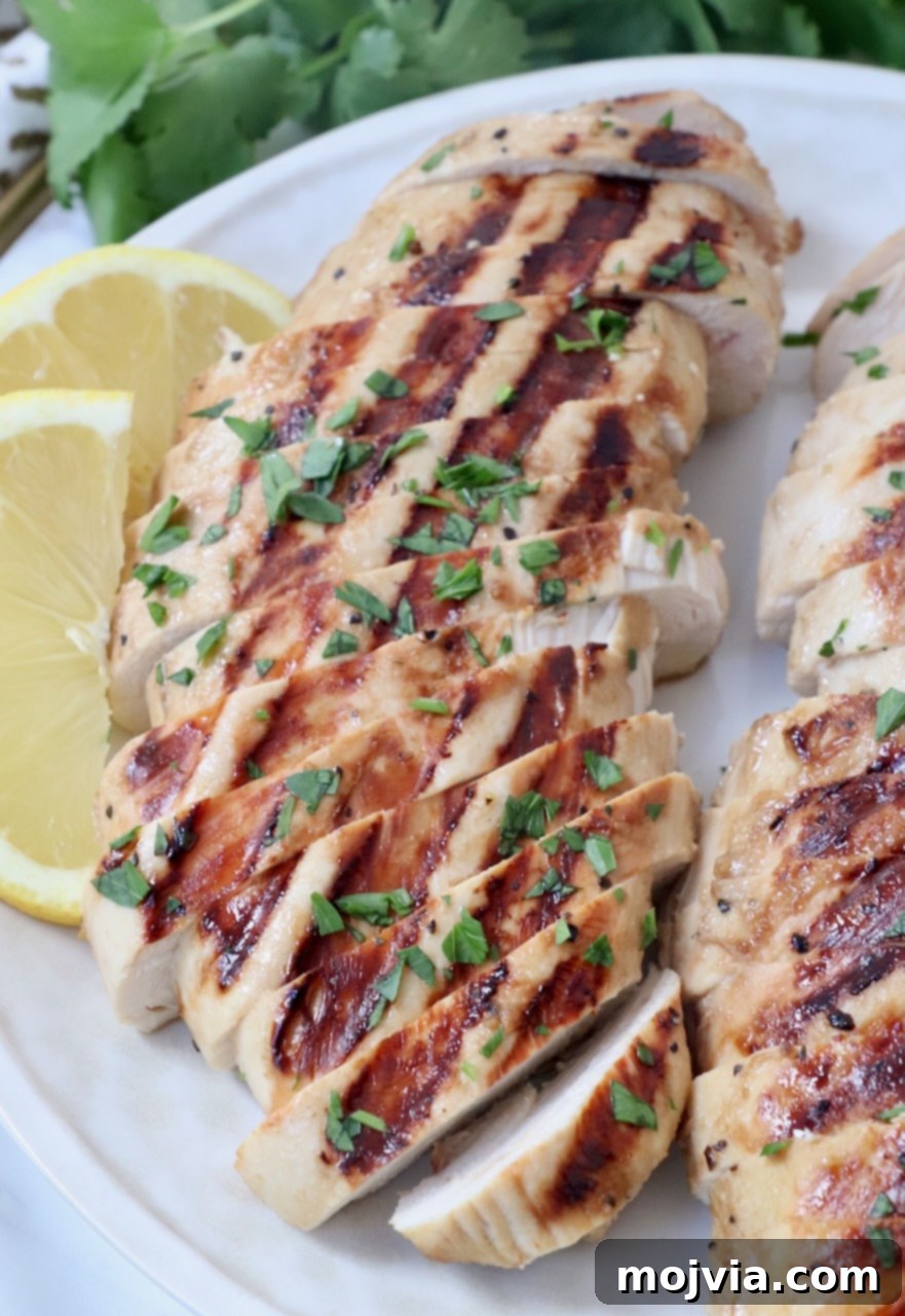 Tender Chicken Elixir 2 Sliced grilled chicken breast served on a plate with fresh lemon wedges, showcasing its juicy texture and rich flavor.