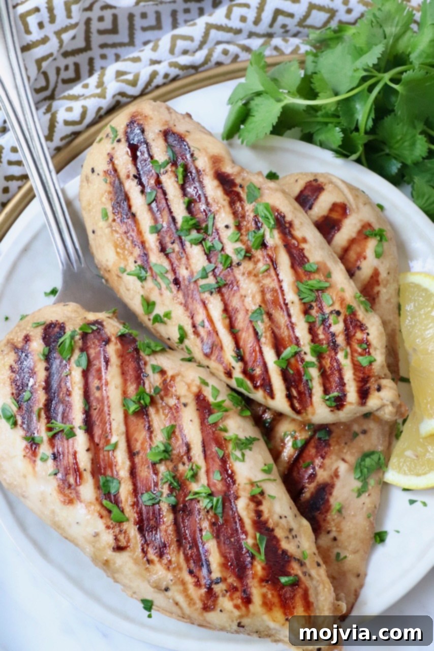 Tender Chicken Elixir 5 Perfectly grilled chicken breasts arranged on a plate with fresh lemon wedges, ready to be served.