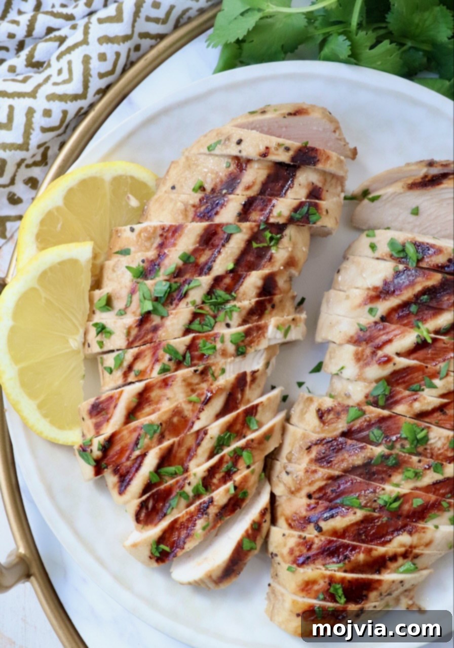 Tender Chicken Elixir 6 Perfectly sliced grilled chicken breasts with a side of fresh lemon wedges on a white plate, ready to enjoy.