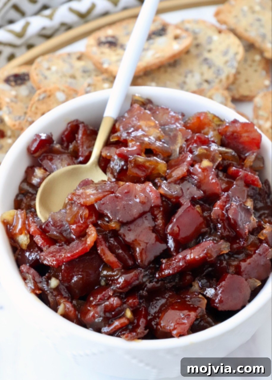 Sweet & Savory Bacon Preserve 15 A large bowl of homemade bacon jam with a serving spoon, highlighting its chunky and appetizing texture.