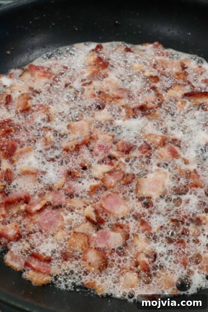 Sweet & Savory Bacon Preserve 5 Diced bacon frying and sizzling in a skillet, rendering its fat and turning golden brown.