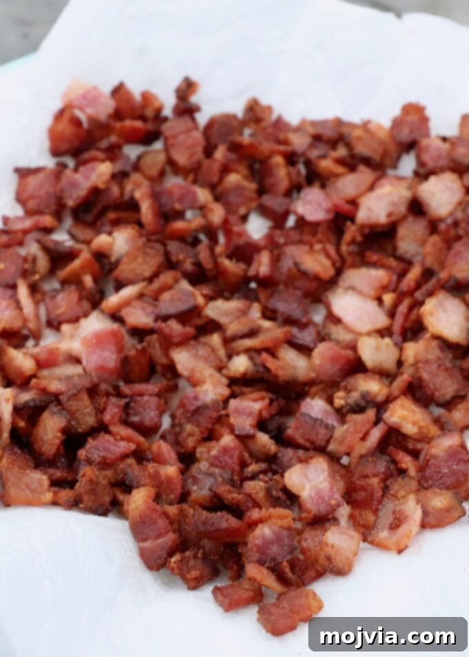 Sweet & Savory Bacon Preserve 6 Crispy, diced cooked bacon resting on a paper towel-lined plate to absorb excess grease.
