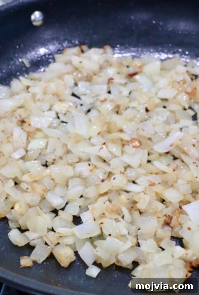Sweet & Savory Bacon Preserve 7 Diced onions cooking in bacon drippings in a skillet, becoming translucent and caramelized.