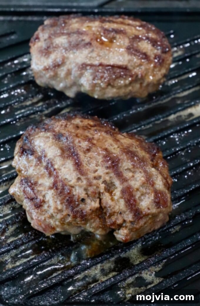 California Dream Burger 5 Burger patties grilling on a cast iron grill pan