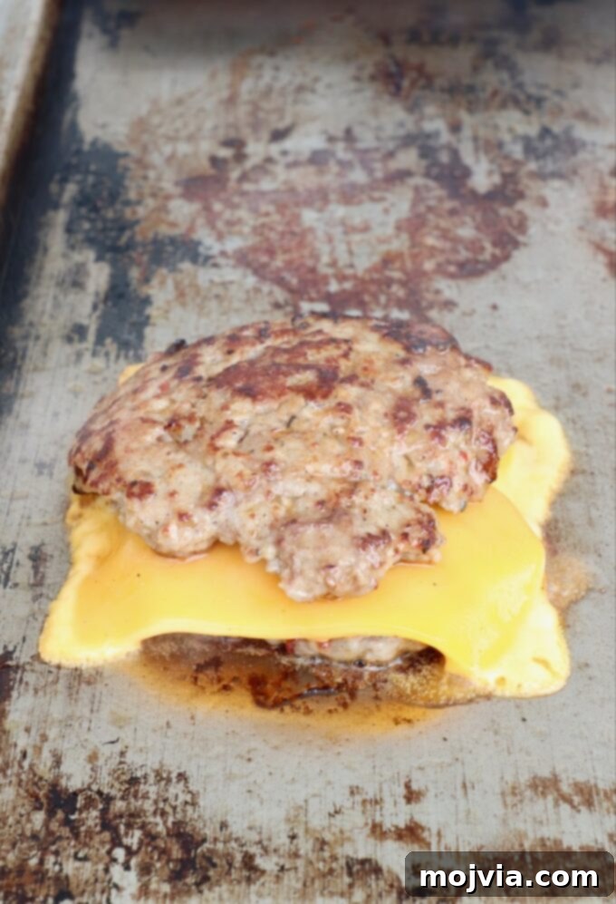 Sunrise Burger 11 Two stacked burger patties with a slice of melted cheese in between, creating a double burger on a flat top.