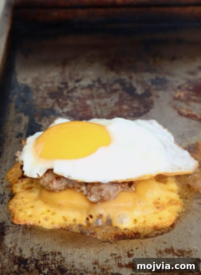 Sunrise Burger 12 A perfectly fried egg placed on top of a cheesy smashed burger patty, still on the flat top griddle.