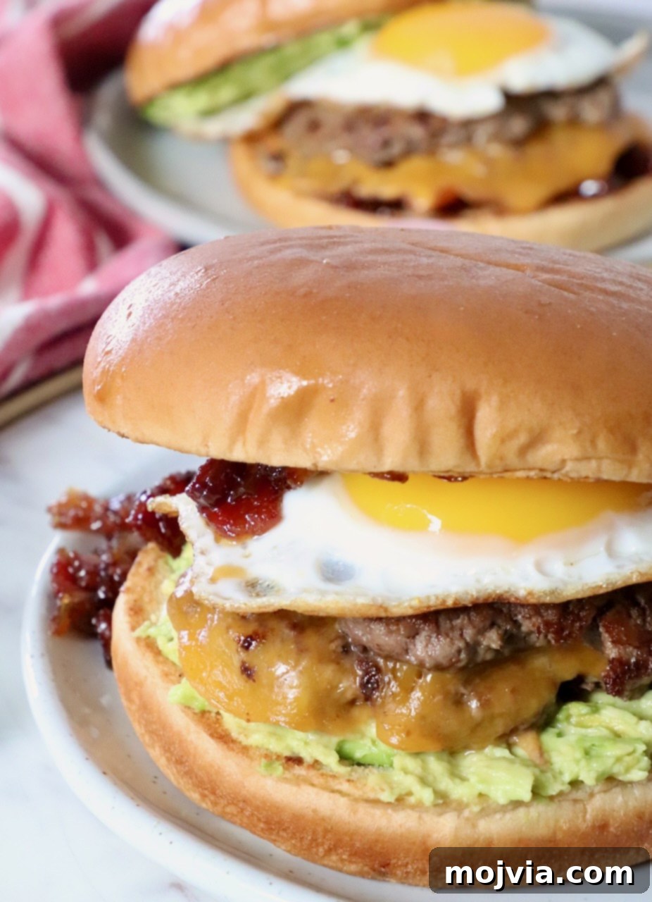 Sunrise Burger 13 A perfectly cooked Breakfast Burger, topped with a fried egg and glistening bacon jam, served on a plate.