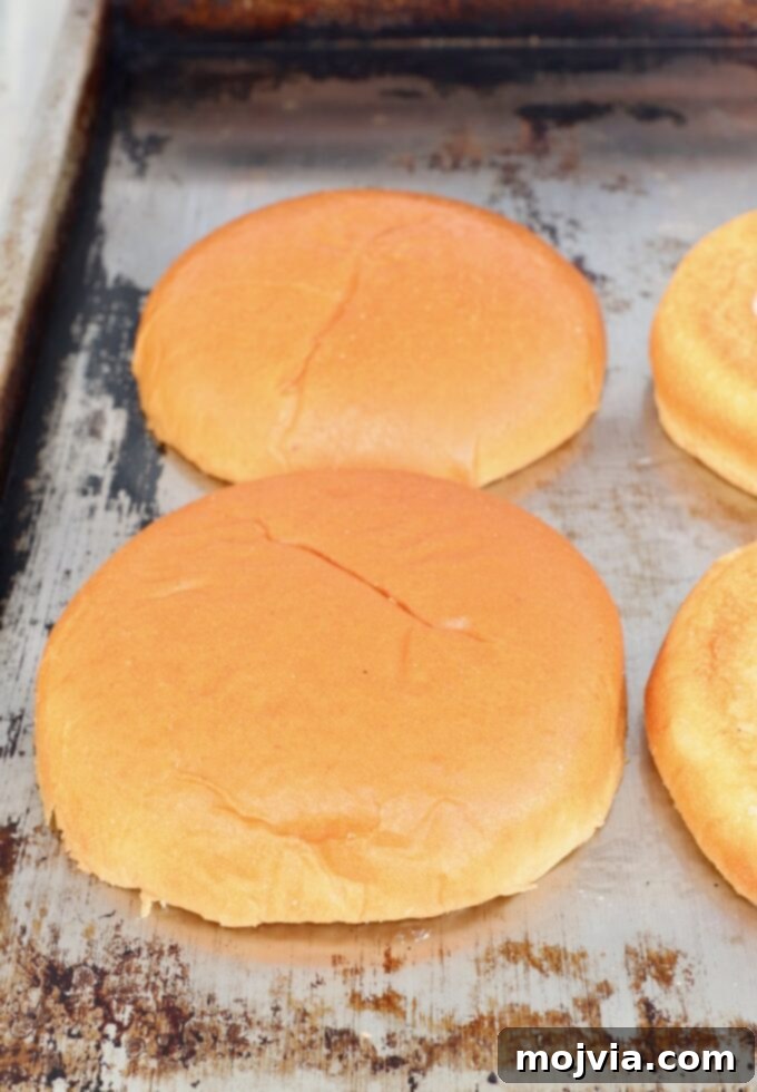Sunrise Burger 5 Hamburger buns toasting face-down on a hot flat top griddle, achieving a golden brown edge.
