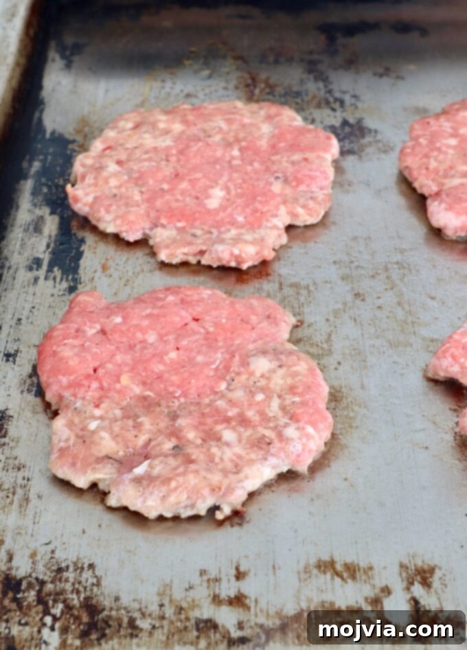 Sunrise Burger 8 Balls of ground beef and sausage being smashed into thin burger patties on a hot flat top griddle.