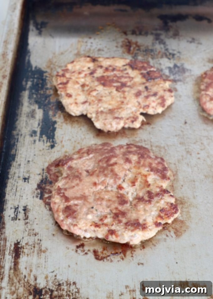 Sunrise Burger 9 Perfectly cooked and seared smashed burger patties on a flat top griddle, showcasing crispy edges.