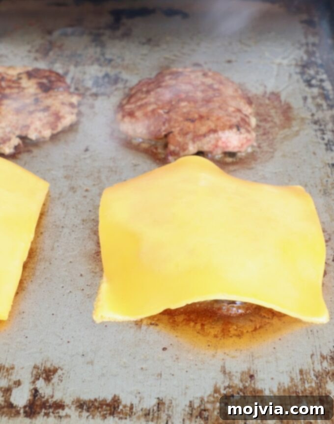 Sunrise Burger 10 Slices of cheddar cheese melting on top of hot burger patties on a flat top griddle.