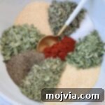 A spoonful of homemade vegetable seasoning, with dried herbs and spices visible, ready for use.