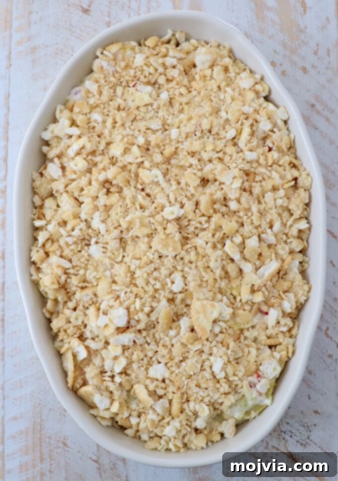 Golden Cheesy Squash Bake 12 The squash casserole assembled with the buttery cracker topping sprinkled generously over the creamy squash base in the baking dish.