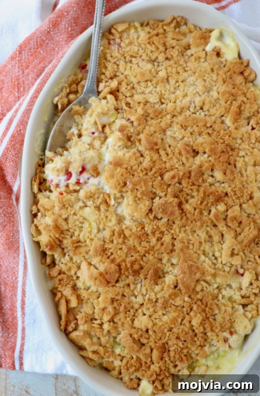 Golden Cheesy Squash Bake 13 Freshly baked squash casserole in a baking dish, with a serving spoon tucked into the creamy, golden dish.
