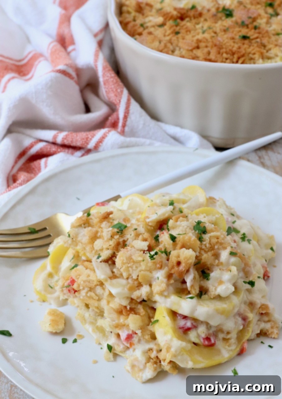 Golden Cheesy Squash Bake 14 A generous serving of creamy squash casserole with its golden, crispy topping on a white plate, ready to be enjoyed with a fork.