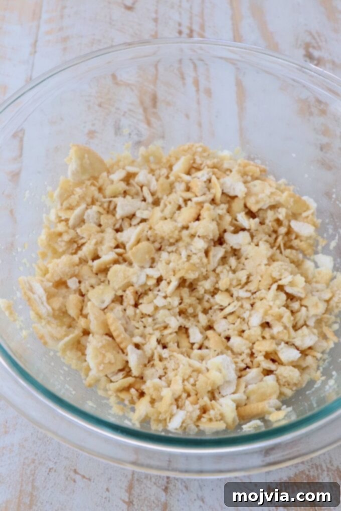 Golden Cheesy Squash Bake 10 Crushed buttery crackers, like Ritz, being mixed with melted butter in a separate glass bowl to create the topping.