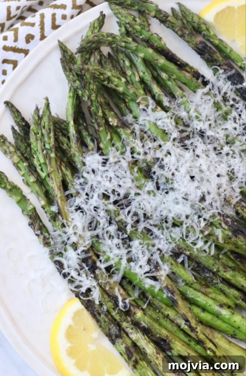 Simple Steps to Delicious Asparagus 14 Grilled asparagus on a plate, generously topped with freshly grated parmesan cheese, ready for serving.